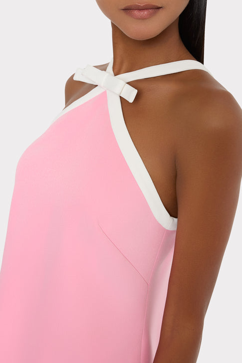 Close-up of a pink dress with white straps on a plain background