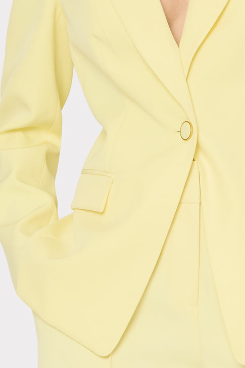 Close-up of a yellow blazer with a button on a light gray background