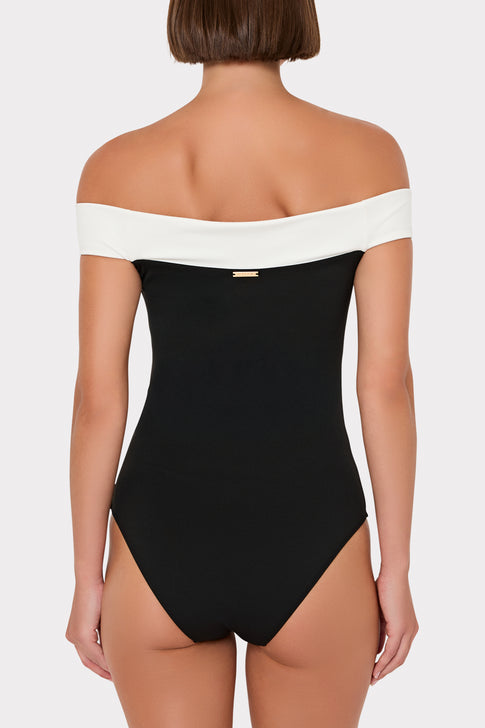 Black swimsuit with white straps on a plain background