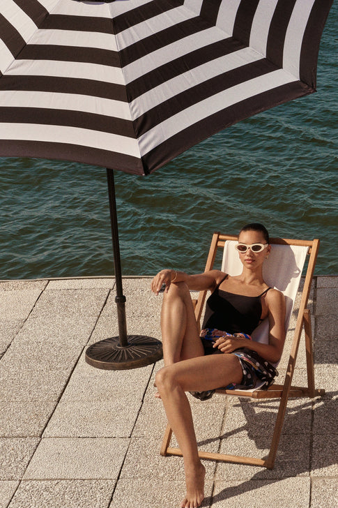 Model in Black Grace Solid One Piece on Lounge Chair - Pool Lifestyle | MILLY